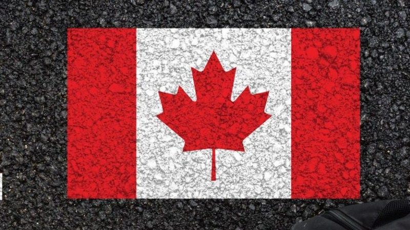 The Canadian flag flying against a city skyline