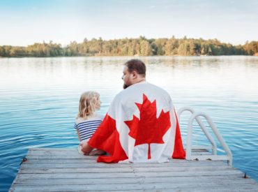 father-and-daughter-wrapped-in-large-canadian-flag-2021-09-13-17-00-48-utc